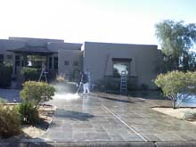 A crew memember power washing the driveway of a home in Phoenix